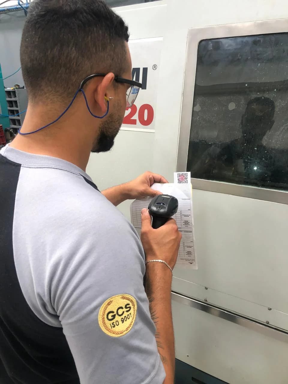 Operador usando leitor de QR Code ao lado do torno CNC
