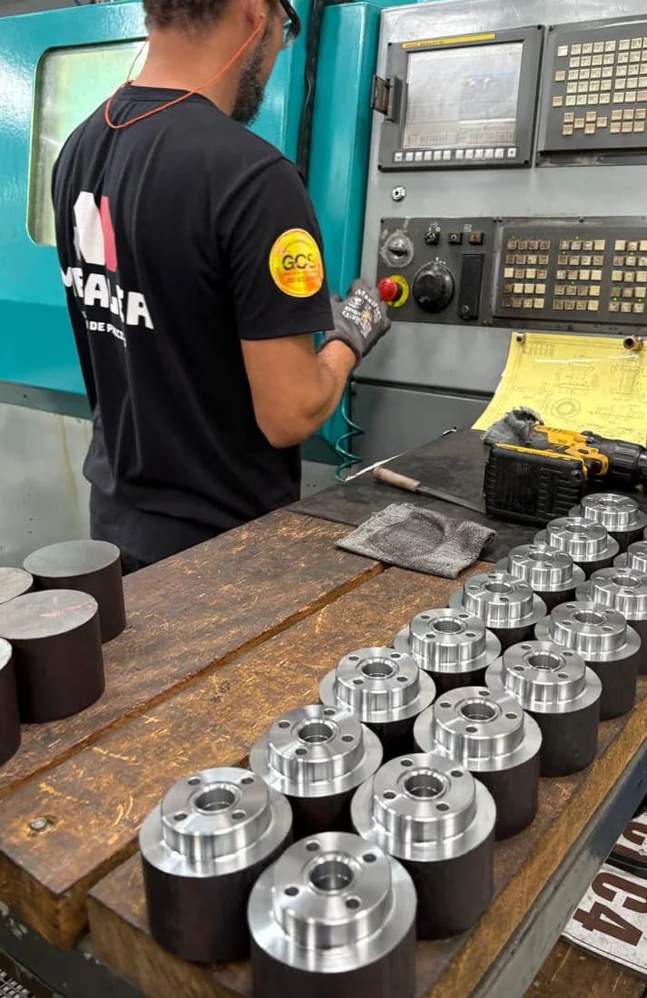 Operador no torno CNC e lote de peças fabricadas pela Metaler